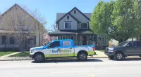 a Roof It Forward truck parked in front of a house
