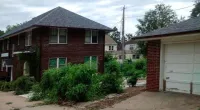 a house with trees in front of a brick building