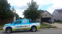 a Roof It Forward truck parked in front of a house