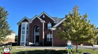 a brick building with a lawn and trees in front of it