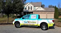 a Roof It Forward truck parked in front of a house