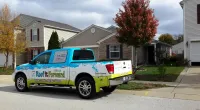 a Roof It Forward truck parked in front of a customer's house