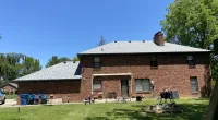 a large brick building with grass in front of a house