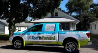 a Roof It Forward truck parked in front of a house