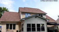 Two-story beige house with brown roof, patio furniture, and blue sky with Roof It Forward charity logo.
