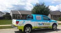a Roof It Forward truck parked in front of a house