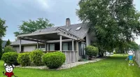 a green field with trees in the front yard of a house
