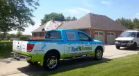a Roof It Forward truck is parked in front of a house