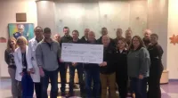 Roof It Forward employees holding a large check