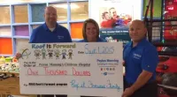 Roof It Forward employees holding a large check