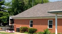 a large brick building with grass in front of a house