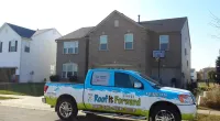 a Roof It Forward truck parked in front of a house