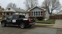 a Roof It Forward truck parked in front of a house