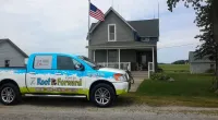a Roof It Forward truck parked in front of a house