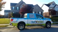 a Roof It Forward truck parked in front of a house