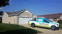 a Roof It Forward truck parked in front of a house