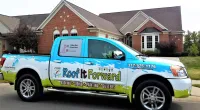 a Roof It Forward truck parked in front of a house