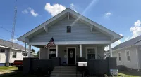Front view of a gray house with an American flag and a mailbox numbered 345 on a sunny day