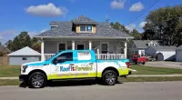a Roof It Forward truck parked in front of a house
