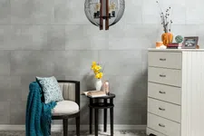 Thumbnail for Cozy reading corner with armchair, teal throw, side tables, flowers, and white dresser against gray wall.