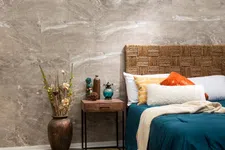 Thumbnail for Cozy bedroom with textured wicker headboard, blue bedding, colorful pillows, wooden nightstand, and vase with dried flowers.