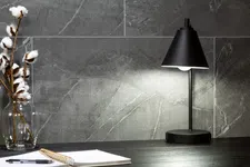 Thumbnail for Modern black desk lamp illuminating workspace with notepad and cotton stems in glass jar on dark surface.