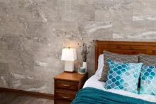 Thumbnail for Cozy bedroom corner with wooden bed, blue patterned pillows, teal throw, nightstand, and table lamp on marble wall.