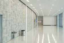 Thumbnail for Bright modern hallway with polished floor, large windows, textured wall, drinking fountain, and trashcan.