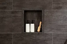Thumbnail for Dark tiled shower niche with two white pump bottles and a wooden bath brush neatly arranged inside