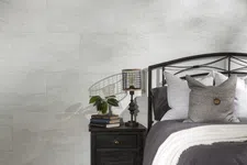Thumbnail for Cozy bedroom corner with dark metal bed, gray bedding, black nightstand, lamp, books, and plant against light stone wall