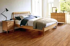 Thumbnail for Bright bedroom with wooden bed, nightstand, dresser, and large windows showing greenery outside.