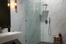Thumbnail for Modern bathroom with marble tiles, glass shower partition, wooden stool, and pendant lighting