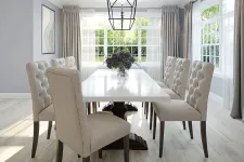 Thumbnail for Bright dining room with a white marble table, beige tufted chairs, large windows, and modern pendant light.