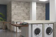 Thumbnail for Modern laundry room with front-load washers, stone tile walls, wooden folding tables, and bright overhead lighting