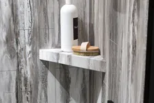 Thumbnail for White pump bottle and wooden brush on marble corner shelf in gray tiled shower area