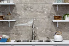 Thumbnail for Modern kitchen sink with stainless steel faucet, white countertop, gray tile backsplash, and open shelves with decor.