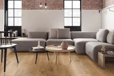 Thumbnail for Modern living room with gray sectional sofa, wooden coffee tables, exposed brick wall, and large arched windows.