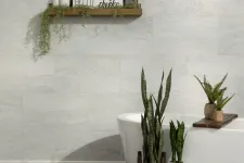 Thumbnail for Modern bathroom with freestanding white tub, green plants, floating wooden shelf, and light gray tiled wall.