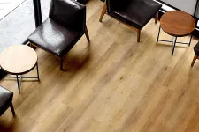 Thumbnail for Modern seating area with dark leather chairs and round wooden tables on light hardwood floor near large windows.