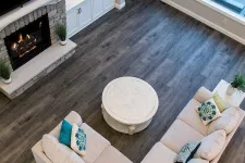 Thumbnail for Cozy living room with beige sectional sofa, round white coffee table, dark wood floor, and lit stone fireplace.