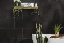 Thumbnail for Modern bathroom with black marble tiles, white freestanding tub, wooden shelf with plants and decor.