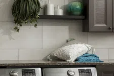 Thumbnail for Modern laundry room with stainless steel washer and dryer, decorative pillows, hanging plant, and ceramic vases.