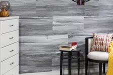 Thumbnail for Cozy corner with white dresser, patterned pillow chair, black side table, gray stone wall, and decorative lighting fixture.