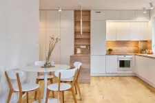 Thumbnail for Modern kitchen and dining area with white cabinets, wooden accents, round table, and wooden chairs on light hardwood floor