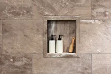 Thumbnail for Two white pump bottles and a wooden brush placed in a stone wall niche with beige marble tiles around.