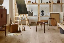 Thumbnail for Cozy art studio with wooden flooring, easel, sculptures, wooden chair, and open shelves filled with art supplies.