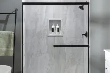 Thumbnail for Modern bathroom shower with glass door, black fixtures, marble tiles, and built-in shelf with bottles.