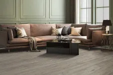 Thumbnail for Modern living room with L-shaped brown sofa, glass coffee table, wooden flooring, and large windows with natural light.