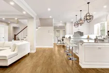 Thumbnail for Open concept kitchen and living area with white cabinets, wood flooring, and modern pendant lights