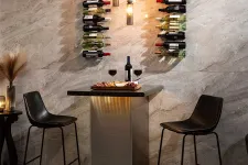 Thumbnail for Modern wine bar setup with two black bar stools, wine bottles on wall racks, and a table with wine and snacks.